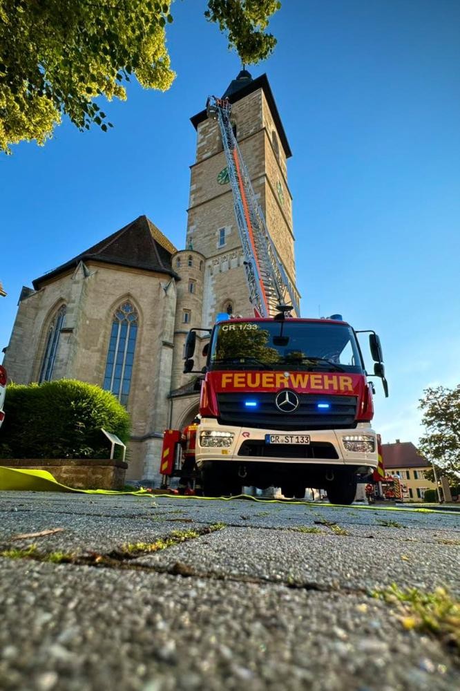 Ein Feuerwehrauto steht vor einem Kirchturm