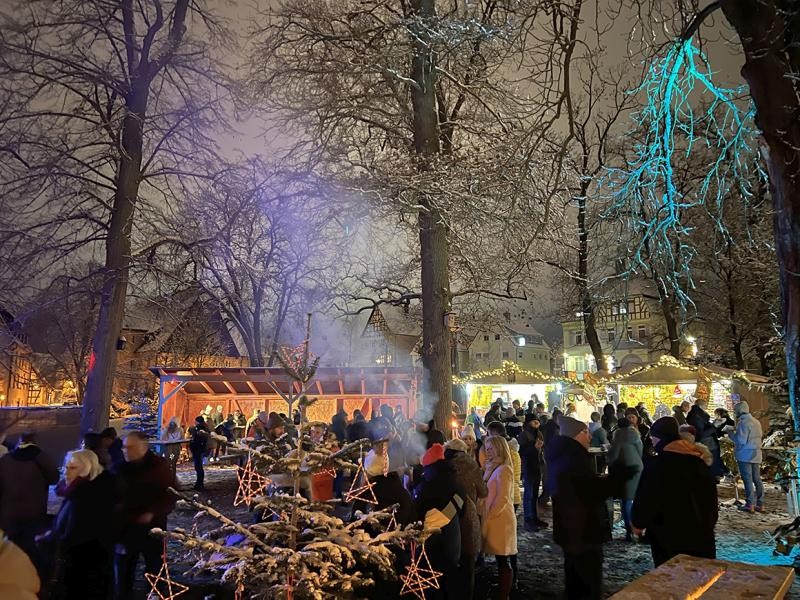 Park weihnachtlich geschmückt mit vielen Menschen um erleuchtete Weihnachtsmarktstände herum