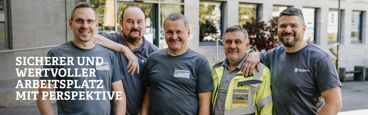 Eine Gruppe von Mitarbeitern aus dem Baubetriebshof stehen vor dem Rathaus und lächeln in die Kamera 