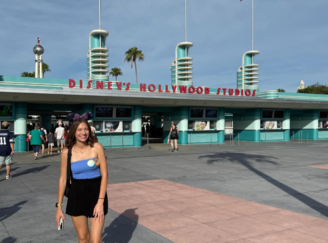 Eine junge Frau steht lachend vor dem Eingang zu den Disney Hollywood Studios