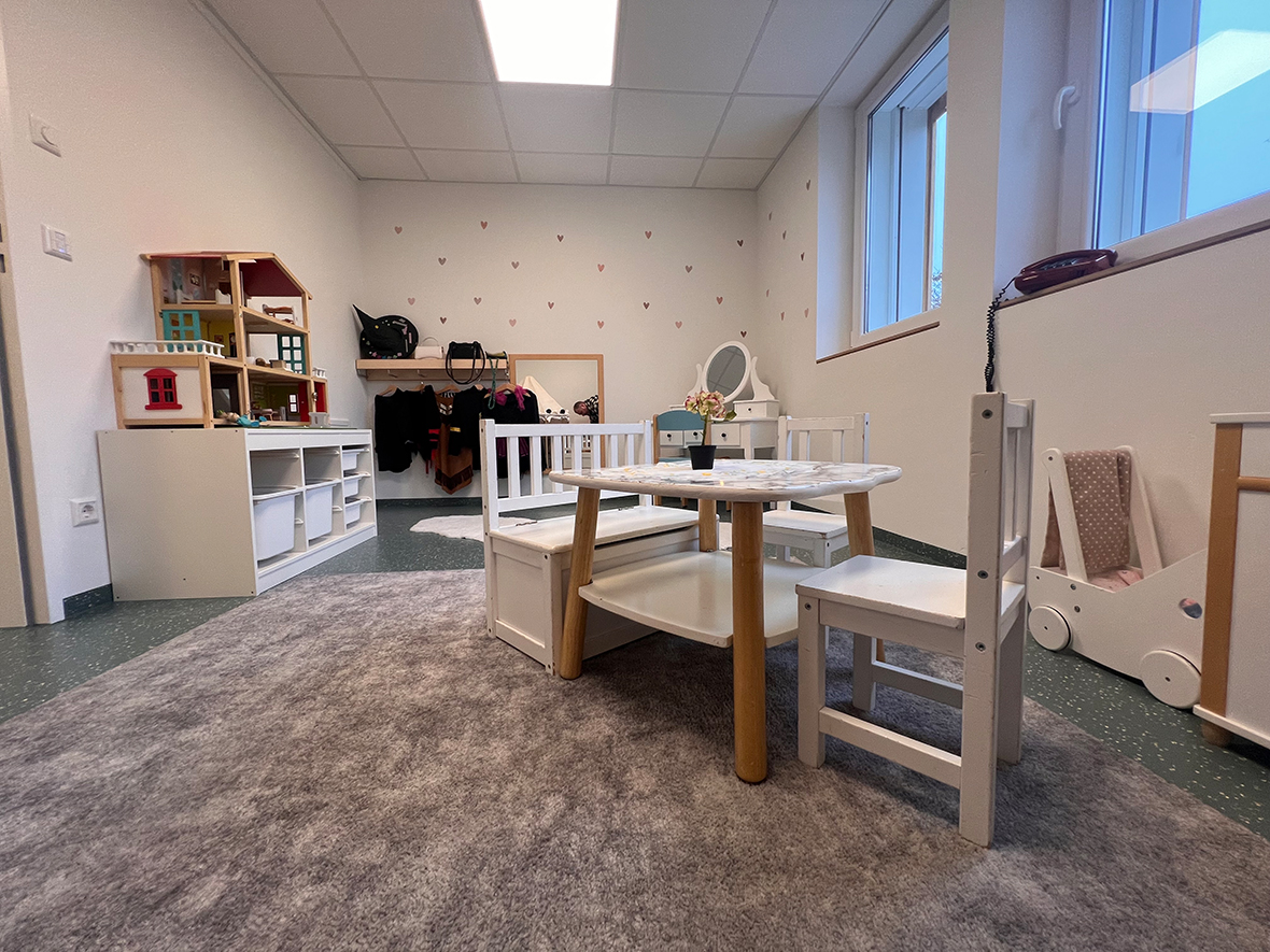 Ein Raum, kindgerecht mit kleinen Möbeln und Schränken in weiß eingerichtet