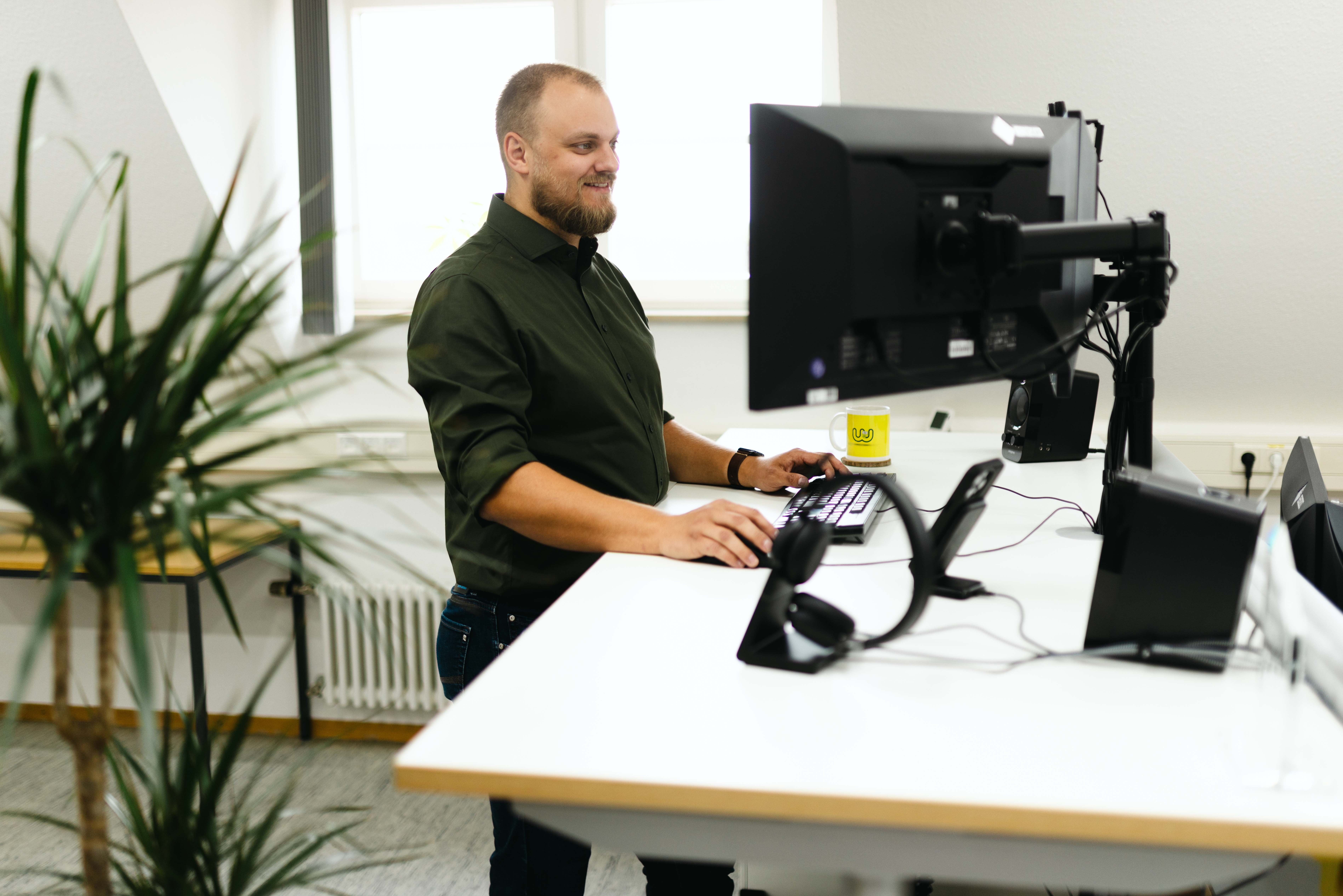Ein Mann steht an einem höhenverstellbaren Schreibtisch