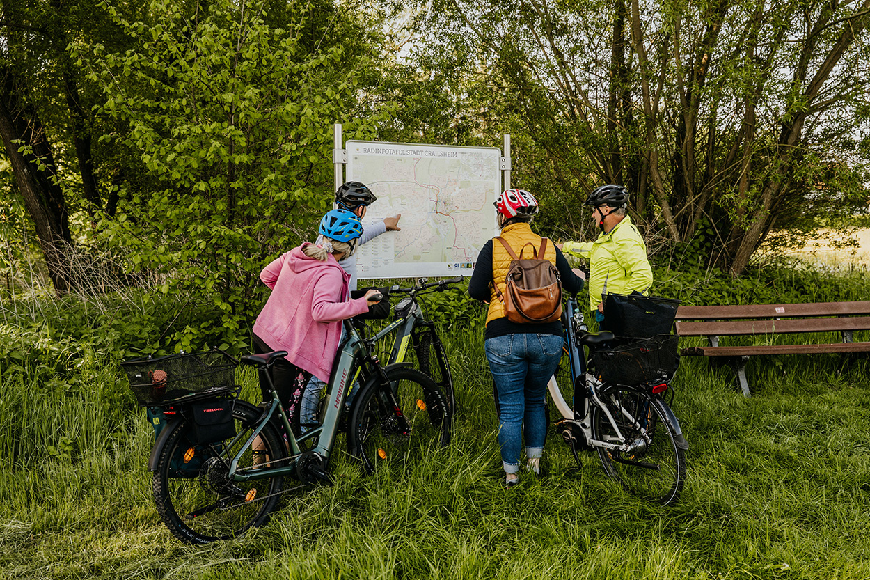 Eine RadfahrerInnen im Grünen vor einer Anzeigentafel