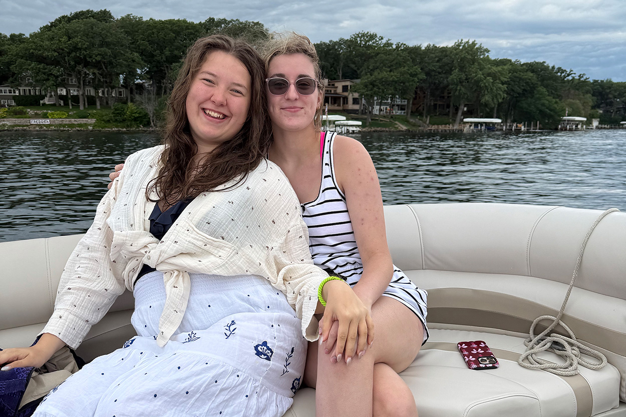 zwei junge Frauen sitzen in einem Boot auf einem See und lachen in die Kamera