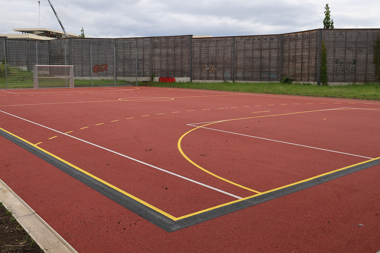 Ein roter Hartplatz mit bunten Spielfeldlinien