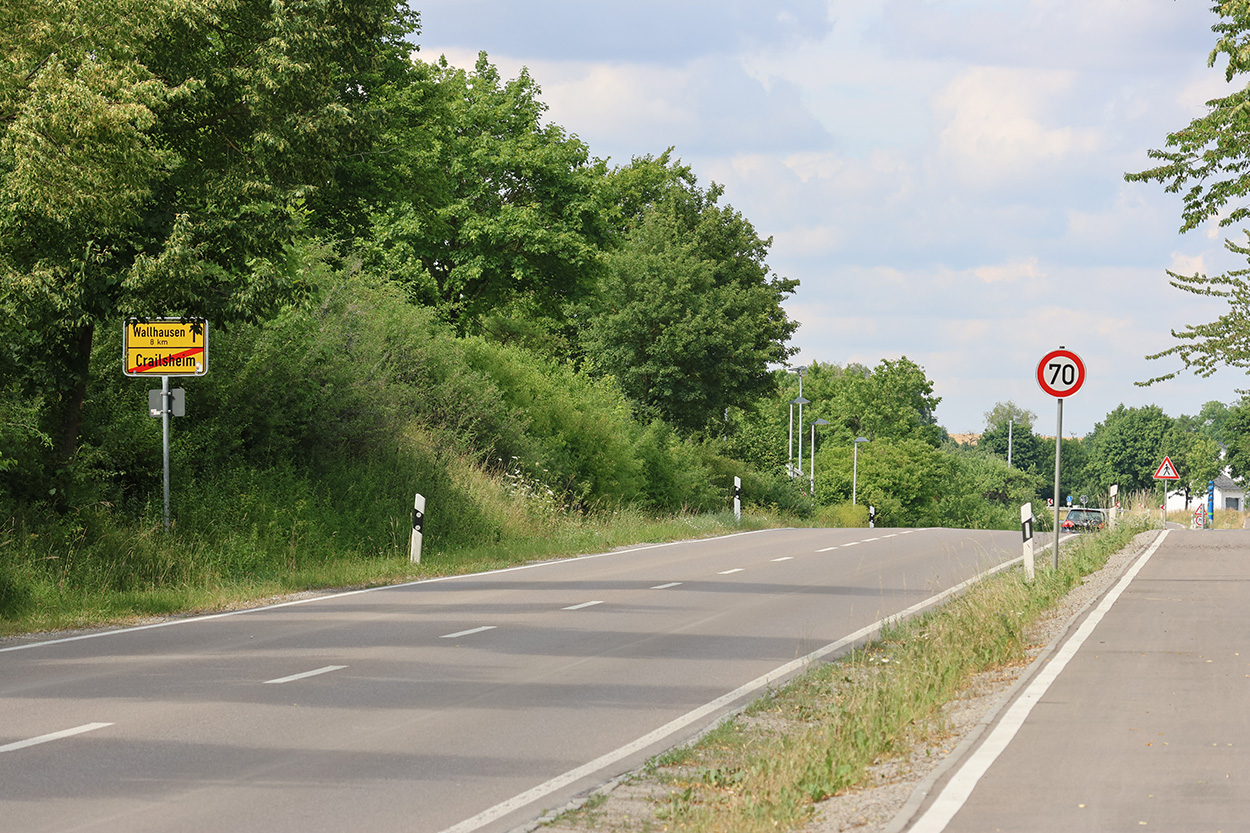 eine Straße, ein gelbes Ortschuild, ein Temposchild 70