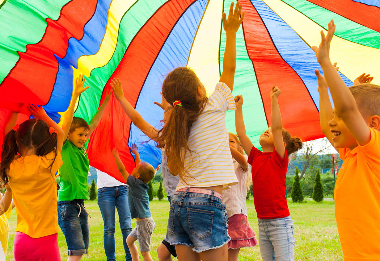 Viele Kinder unter einem bunten Fallschirm