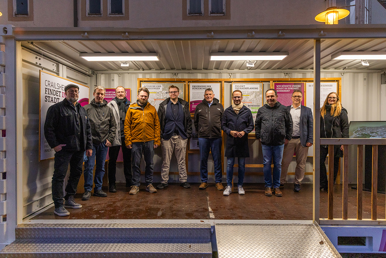 Eine Gruppe von Leuten steht in einem beleuchteten Container, in dem eine Ausstellung zu sehen ist