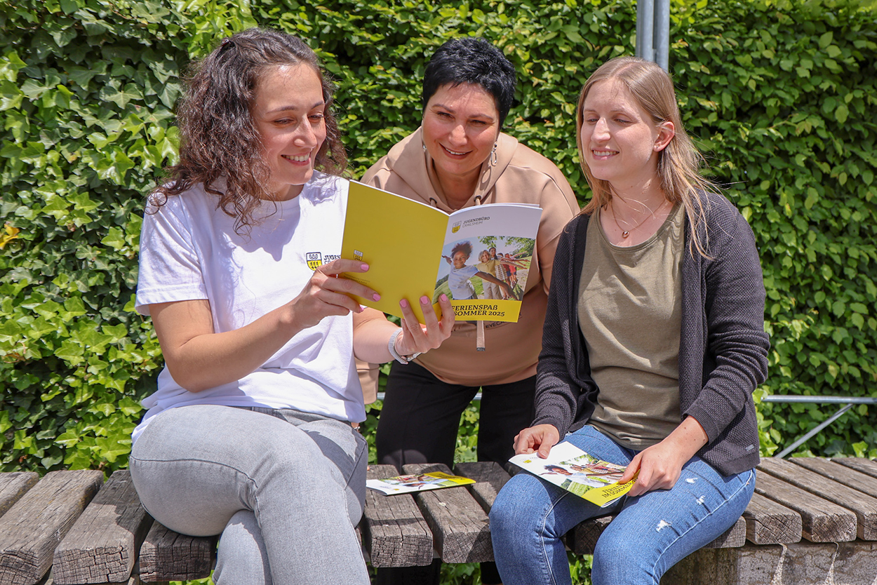 drei Frauen sehen sich eine Broschüre an